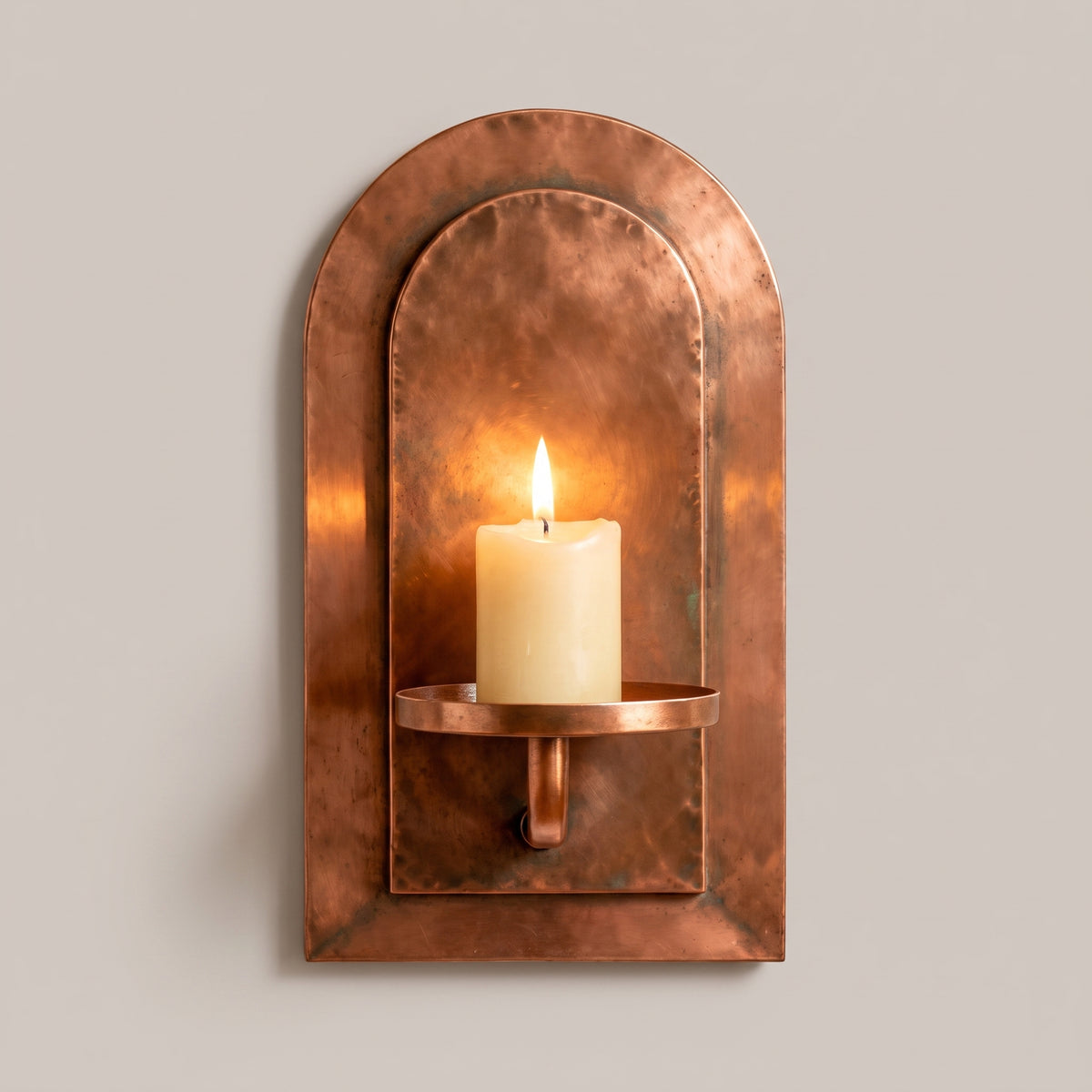 Marrakech Arch handcrafted aged red copper wall candle sconce with a lit pillar candle by Sahara Collection.