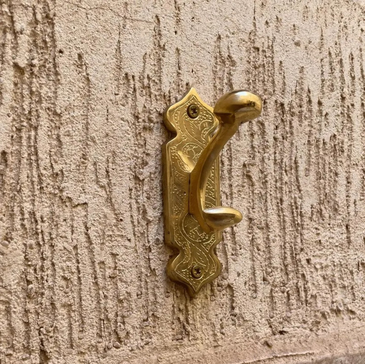 Antique brass Moroccan wall hook mounted on textured wall