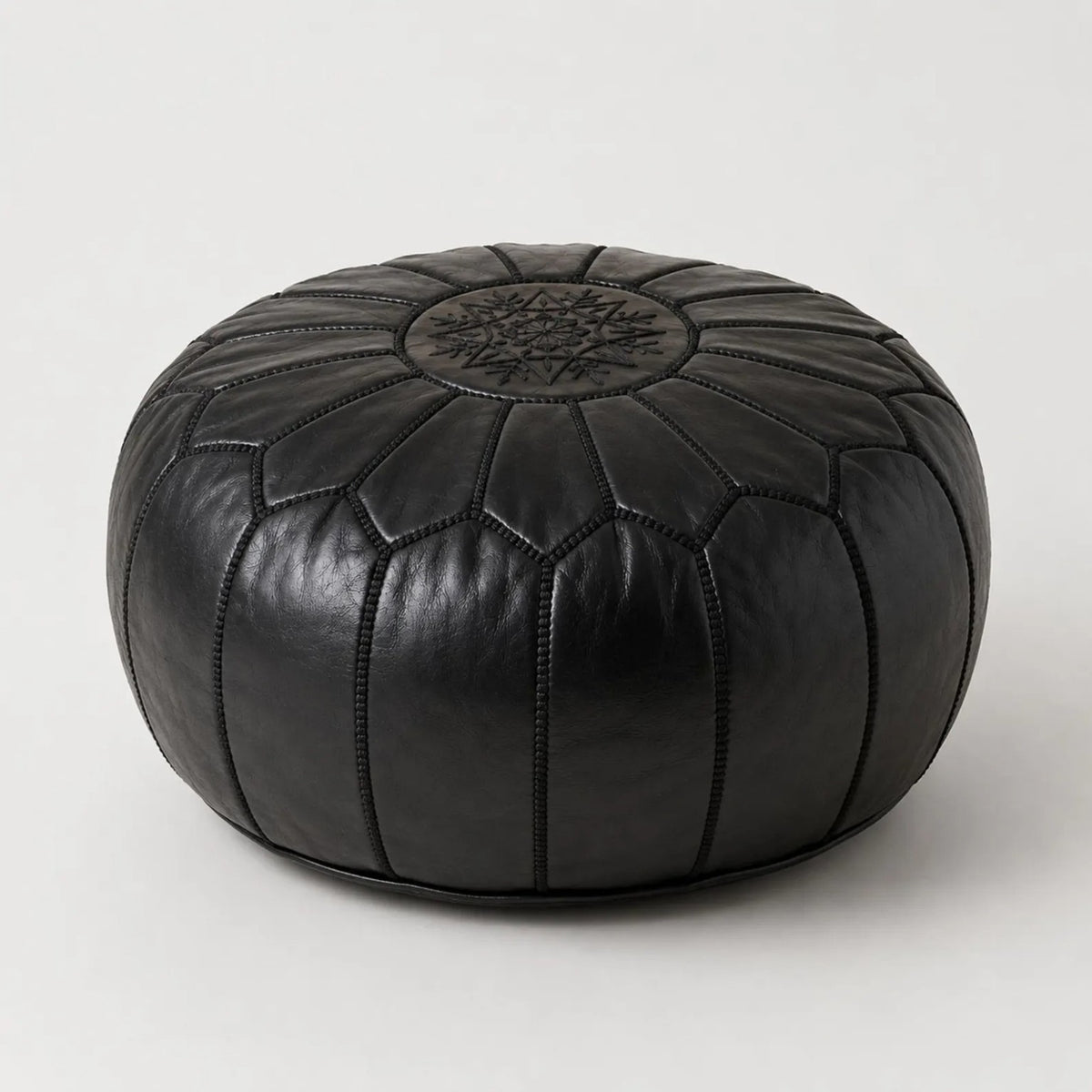 Handcrafted black Moroccan leather pouf on a neutral studio background