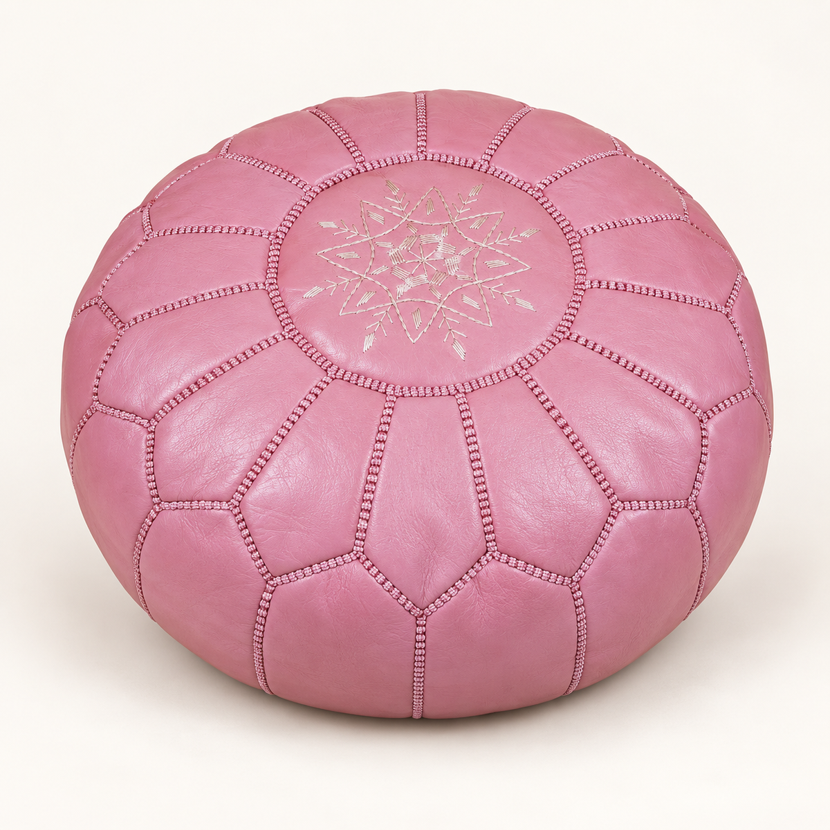 Blush pink Moroccan leather pouf on a white background