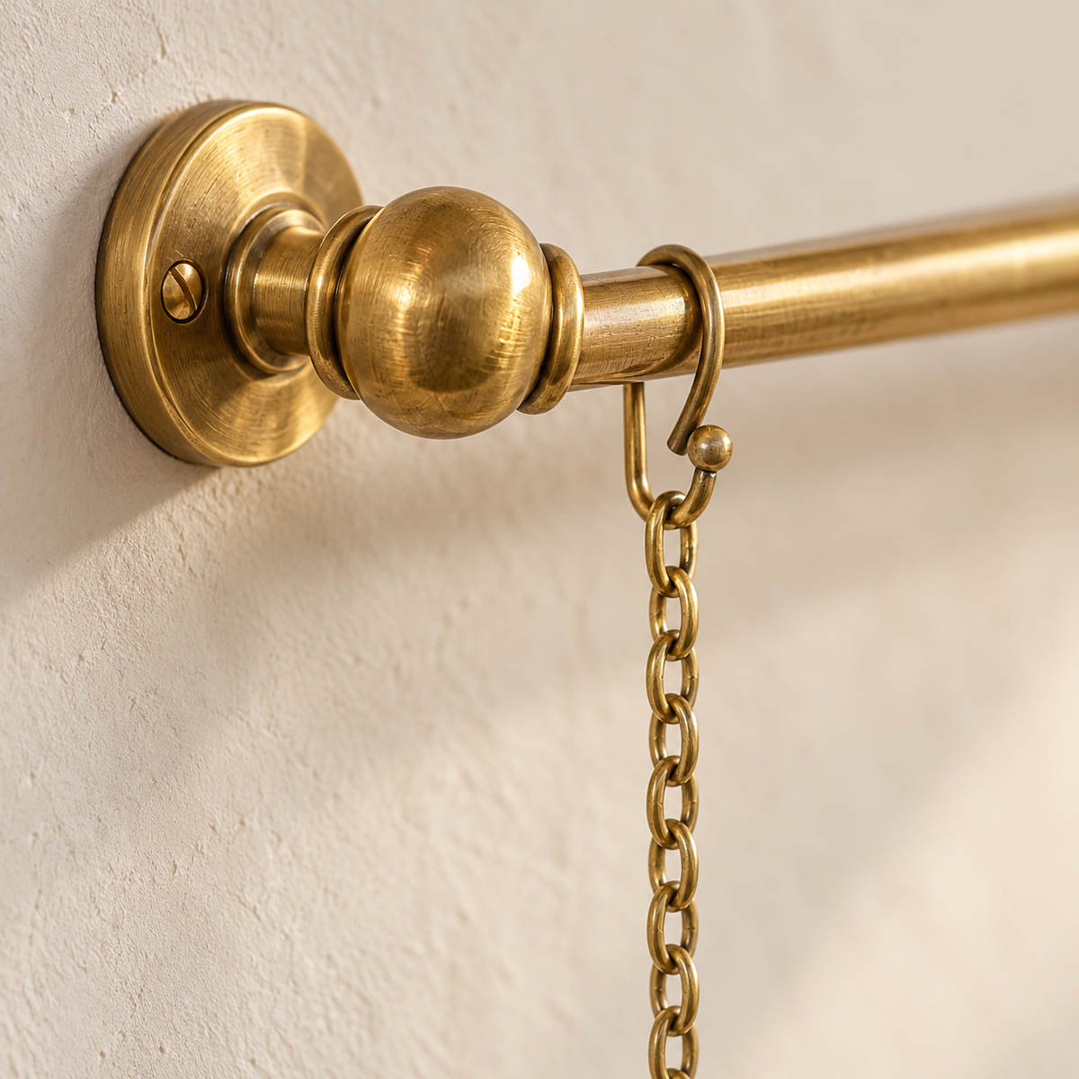 Close-up of handcrafted unlacquered brass picture rail mount and chain