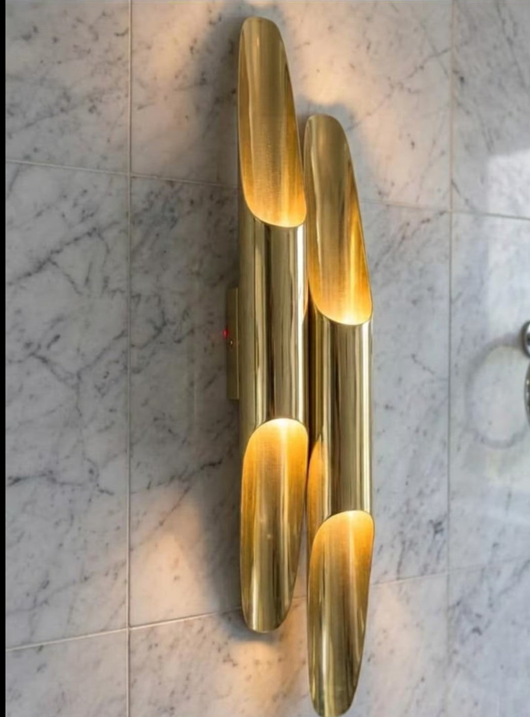 Pair of elongated brass wall sconces on a marble wall