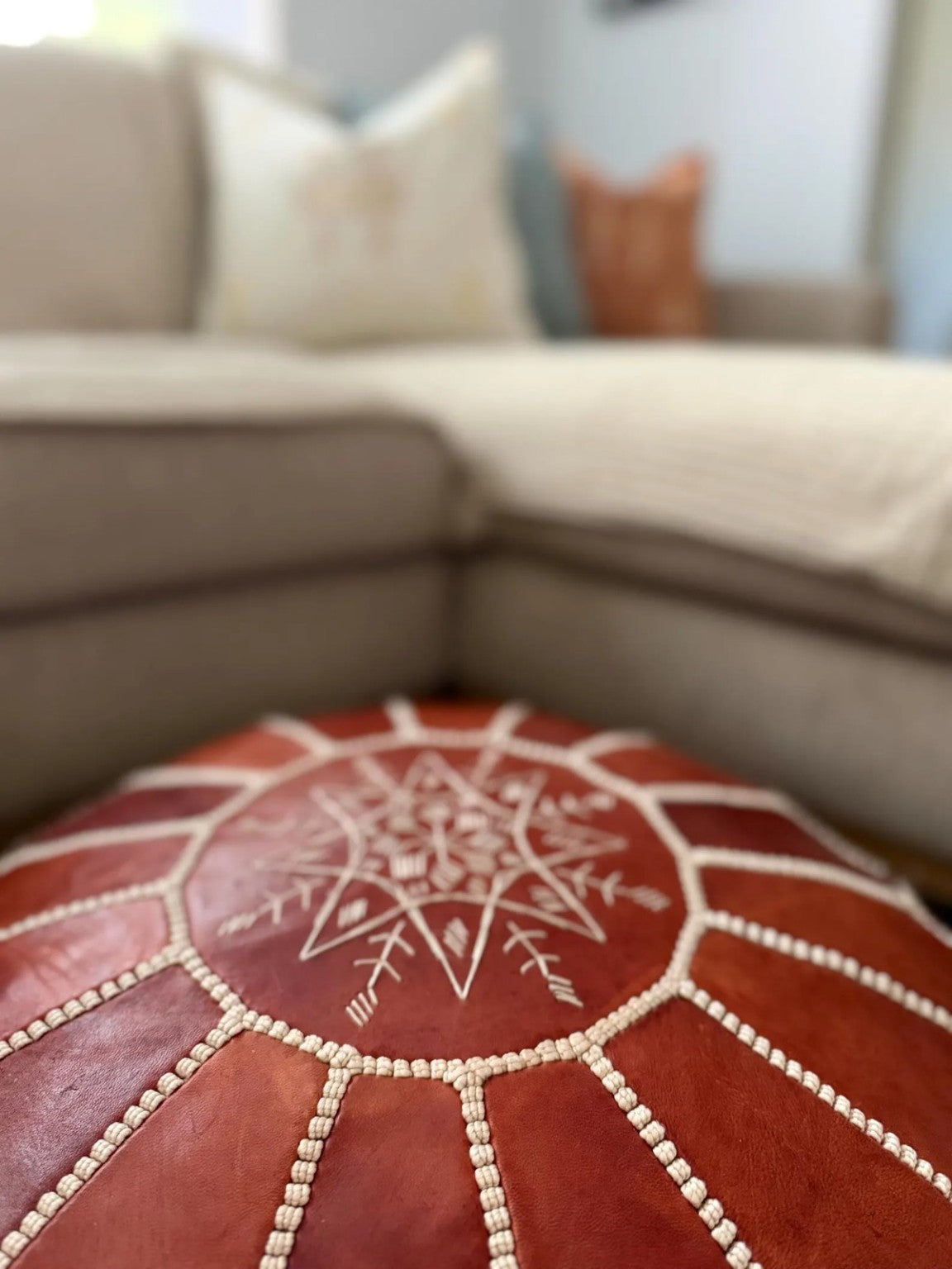 Lifestyle close-up of the embroidered centre on a cognac Moroccan leather pouf