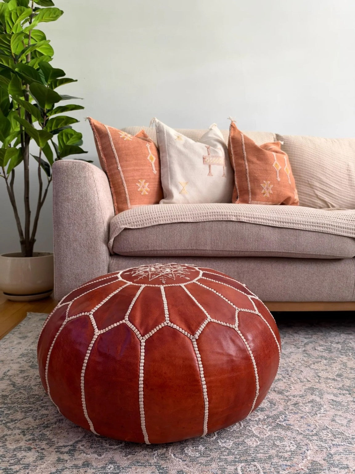Cognac brown Moroccan leather pouf styled in a contemporary living room
