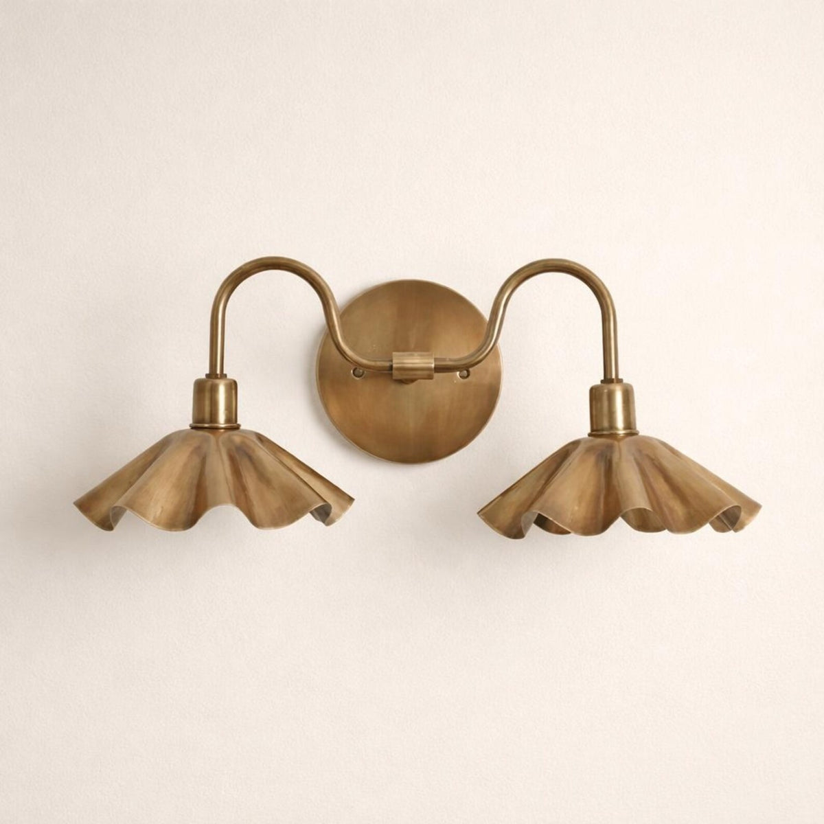Double petal brass wall sconce styled on a green interior wall