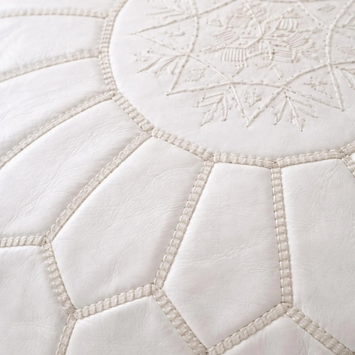 Close-up of hand stitching and embossed motif on white Moroccan leather