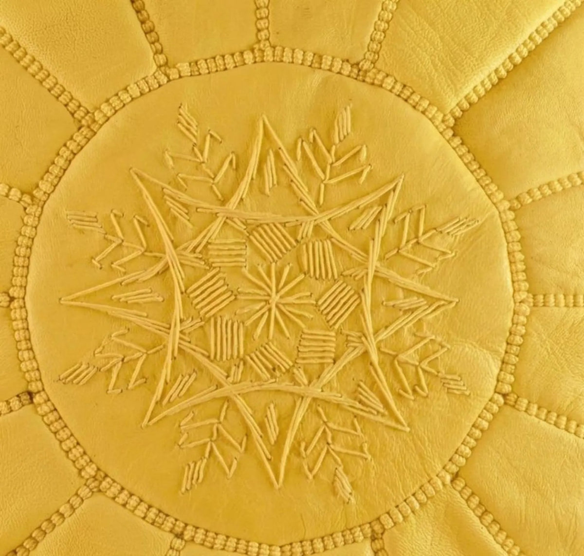 Close-up of tonal hand embroidery on a mustard yellow Moroccan leather pouf
