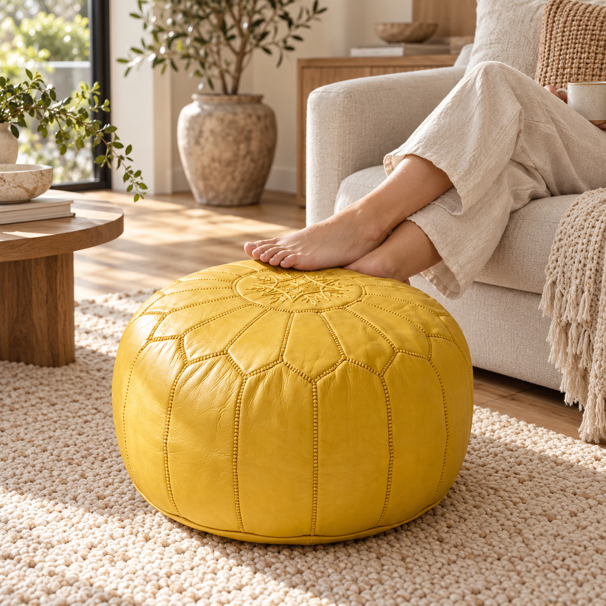 Person relaxing with feet resting on a mustard yellow Moroccan leather pouf