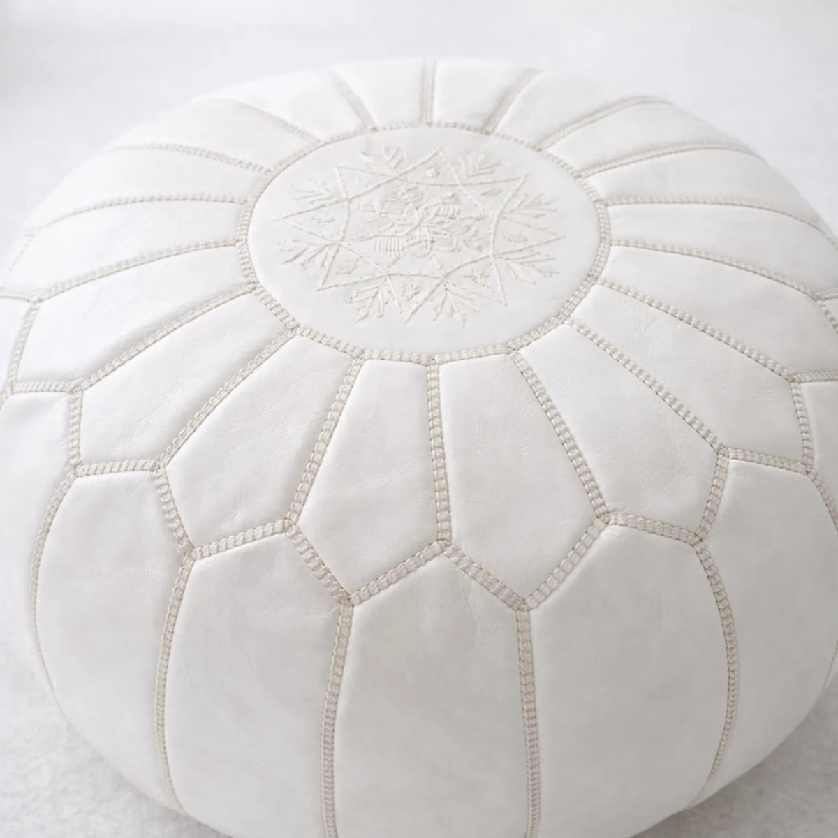 Artisan detail of the white leather pouf top and traditional embroidery
